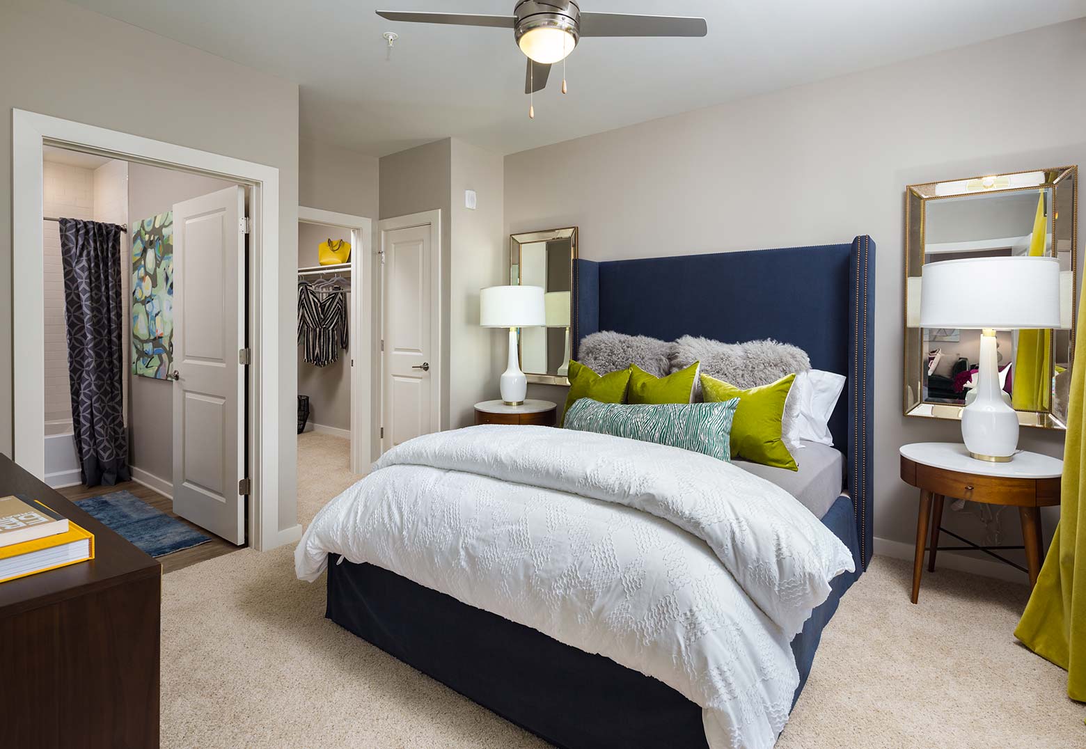 A stylish bedroom adorned with two elegant lamps, two sleek mirrors, and a large ceiling fan.